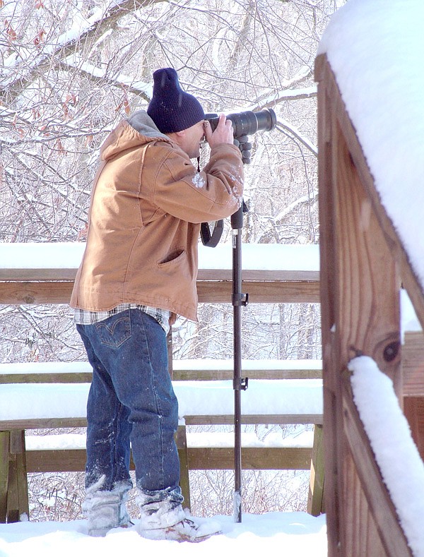 Photographing wildlife | Terry Stanfill, manager of the Eagle Watch Nature Area, watches eagles and other waterfowl through the lens of his camera on Saturday when the Northwest Arkansas Audubon Society visited the nature area watching for birds and other wildlife in the snow. About seven people braved the cold and snow to participate in the NWAAS field trip. The group observed more than 25 bald eagles on Saturday morning.
