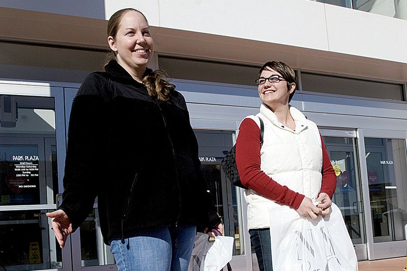 Sylvia Bastian (left) of Alexandria, Va., and Christina Colby of Sacramento, Calif., wait for a ride Thursday afternoon outside Park Plaza. They were disappointed to find many of the stores in the Little Rock mall closed. 
