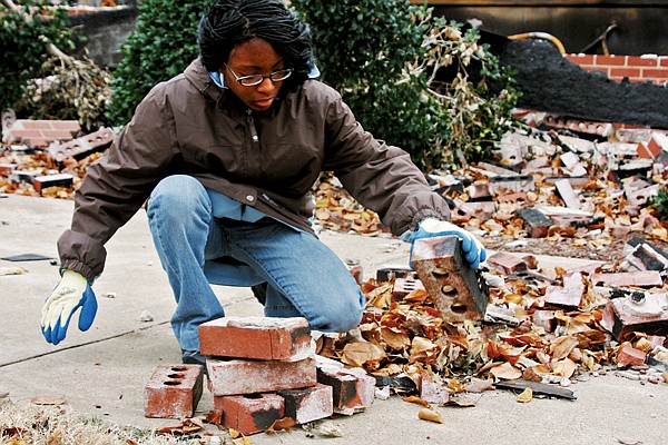 Lyon College student Miracle Davis of Little Rock picks up charred bricks from Edwards Commons. The bricks and other debris were used as props for the college’s spring production of The Trojan Women.