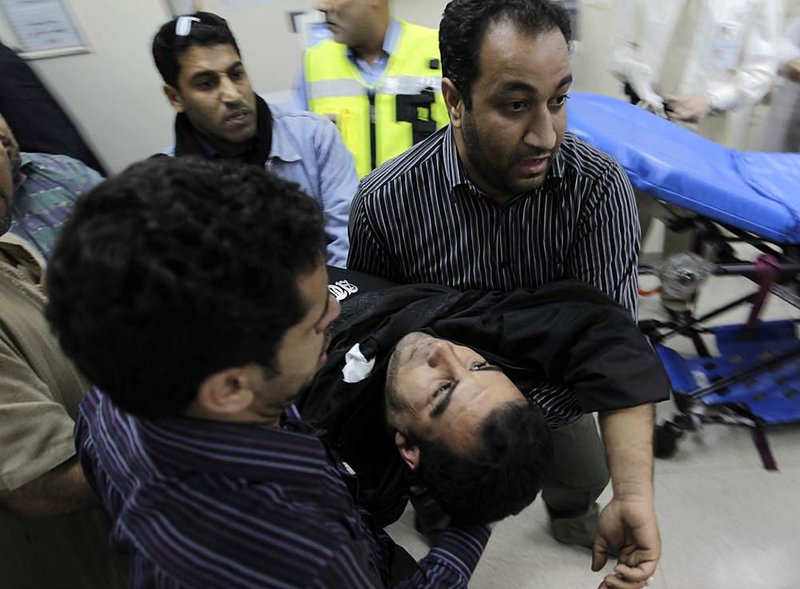 Bahrainis carry an injured anti-government protester to a hospital in Manama early Thursday after riot police moved against the demonstrators. 