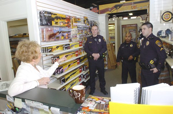 Sue Secker, manager of the Daisy Air Gun Museum downtown, chats Thursday with Rogers police officers, from left, John Alexander, Mario Garcia and Jared Robinson.
