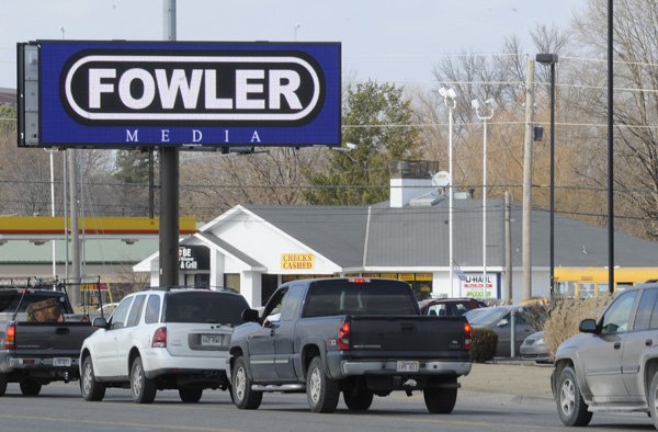 An electronic billboard advertises Thursday at the corner of Walton Boulevard and Southwest 14th Street in Bentonville. An ordinance passed in June 2010 allows the billboards as long as four traditional billboards are removed for each electronic face.

