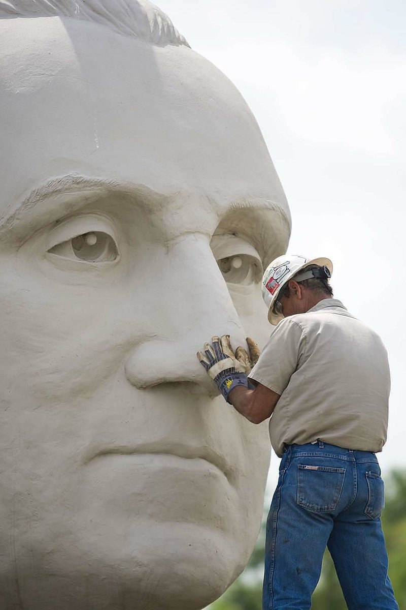 A worker settles a giant head of George Washington onto its shoulders on the front lawn of the Clinton presidential library. The gigantic bust will be open for visitors April 1. 