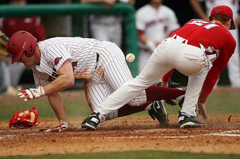 Arkansas’ Jarrod McKinney (left) scores on a wild pitch during the Razorbacks’ seven-run bottom of the third inning in Saturday’s 9-2 victory over Delaware State. 