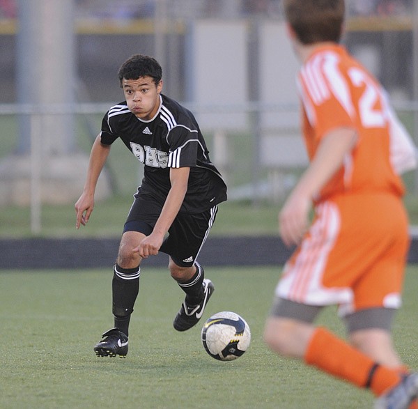 Bentonville’s Brian Flores pushes the ball up the field April 9 while hosting Heritage High School.