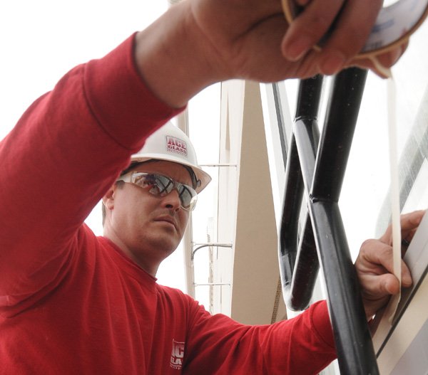 Michael McNicols of Ace Glass tapes a front window frame on Feb. 15 for caulking at the Walmart Visitor Center in Bentonville. The renovation and expansion of the center is expected to be completed in late spring, according to Alan Dranow, Walmart’s director of brand communication.