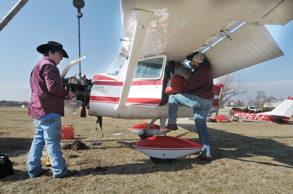 Aaron Cooper, left, watches as Garrett Bradley empties a fuel tank Tuesday on a single-engine 1966 Cessna 150G that crashed on the lawn of the Jones Center in Springdale. Cooper and Bradley of Dawson Aircraft in Clinton were hired to transport the plane to their facility where it will be locked up by the National Transportation and Safety Board. The pilot and a passenger survived the crash during their approach to the Springdale Airport on Feb. 12.