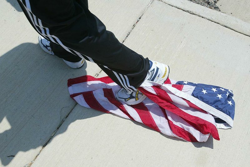 Jonathon Phelps of Westboro Baptist Church in Topeka, Kan., drags a flag on the ground in June 2006 at the Arkansas funeral for Army Spc. Bobby West of Beebe, who was killed in Iraq.

