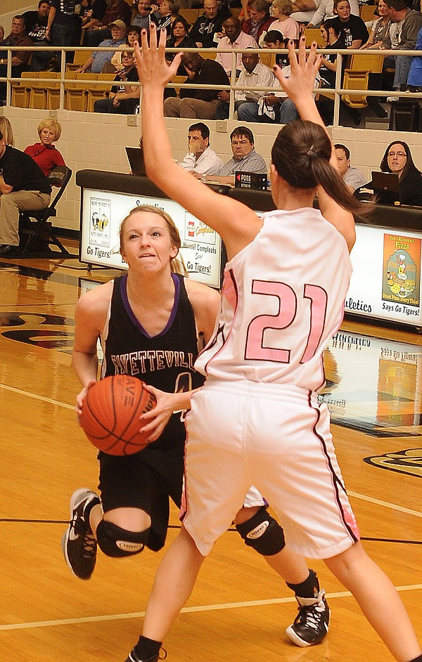 Fayetteville’s Sarah Smith drives the lane while being guarded by Bentonville’s Brittany Spychalski in Tiger Arena on Friday in Bentonville.