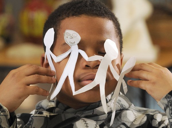 Fourth-grader Devan Holloman appears satisfied with the cutouts he made to help illustrate the book “The Doll People” in an art class Monday at Central Park Elementary School in Bentonville on Monday. The entire school district is reading the book as part of the One District, One Book reading program.