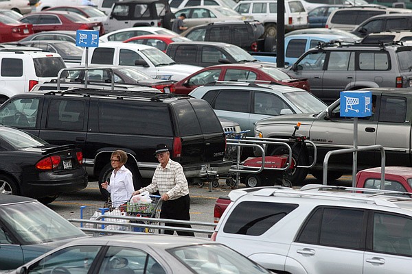 FILE — Customers make their way through a crowded Wal-Mart parking lot in Fayetteville. Wal-Mart Stores Inc. is reporting a 27 percent increase in fourth-quarter net income Tuesday, Feb. 22, 2011.