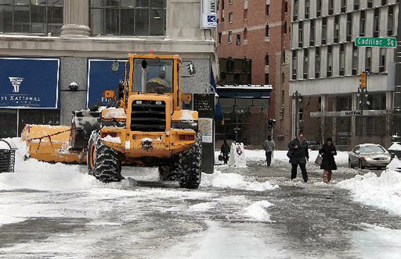  A front-end loader clears snow from the sidewalk Monday in Detroit. About 10 inches of snow fell during the night. 
