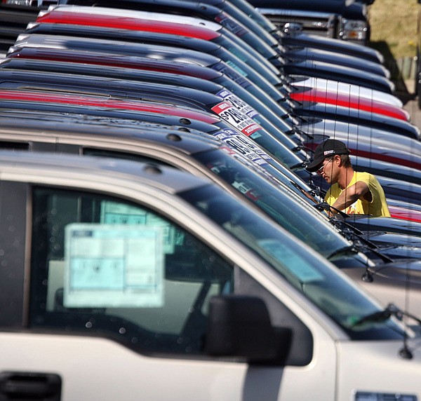 FILE - In this April 21, 2006 file photo, a man wipes down one of the pickup trucks stacked in a long row of 2006 Ford F-150s sitting on the lot of a Ford agency in the south Denver suburb of Centennial, Colo. Ford Motor Co. said Wednesday, Feb. 23, 2011, it will recall nearly 150,000 F-150 pickup trucks to fix air bags that could deploy without warning. The government had raised concerns about the problem. 
