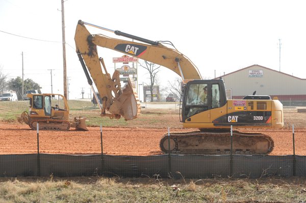 Workers with Arco Excavation and Paving in Springdale operate a bulldozer and an excavator Wednesday to compact a layer of clay as construction begins for a planned Walmart location in Gentry.