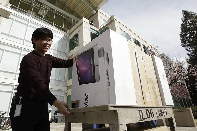 An Apple employee rolls computers into Apple’s Cupertino, Calif., headquarters Wednesday during a shareholders meeting. Investors at the meeting passed a measure to change how board members are elected. 
