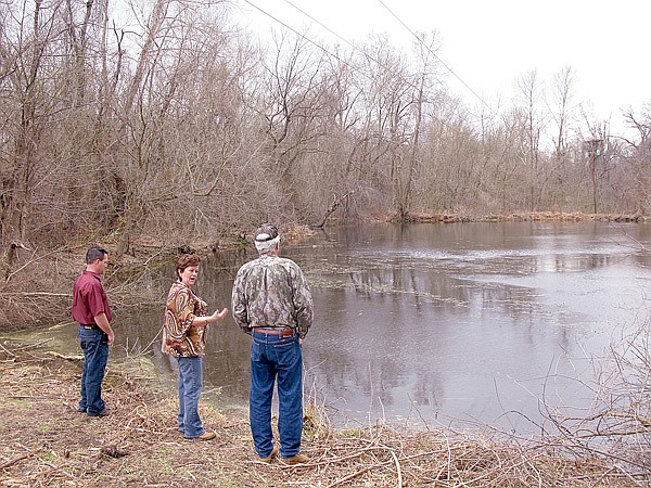 Arkansas Game and Fish Commission region 1 Stream Team coordinator David Evans, right, looks over a pond as Gentry Chamber of Commerce executive director Bev Saunders asks a question while touring the site of a proposed park near Gentry on Feb. 17. Also shown is Gentry Mayor Kevin Johnston. 