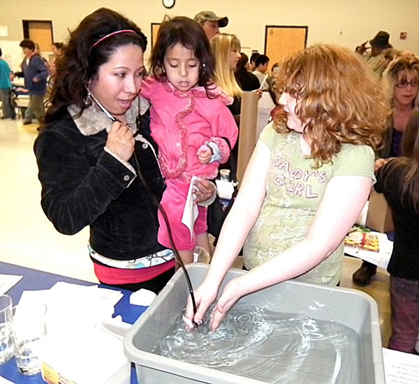 Dinora Regalado and her 4-year-old daughter Beyance listed to underwater sounds through a stethoscope with the help of Summer Gunter. 