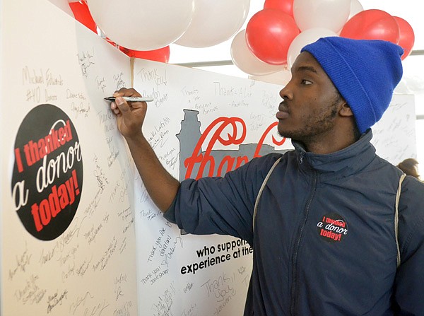 University of Arkansas at Fayetteville sophomore Denis Rugira of Rwanda signs a giant card Wednesday during the first UA Thank a Donor Day. Campus officials held the event to bring attention to donations made to the university.