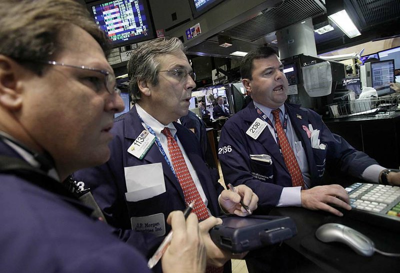 Specialist Stephen Steinthal (right) works Thursday with traders at the New York Stock Exchange, where several companies saw gains after better-than-expected earnings. 