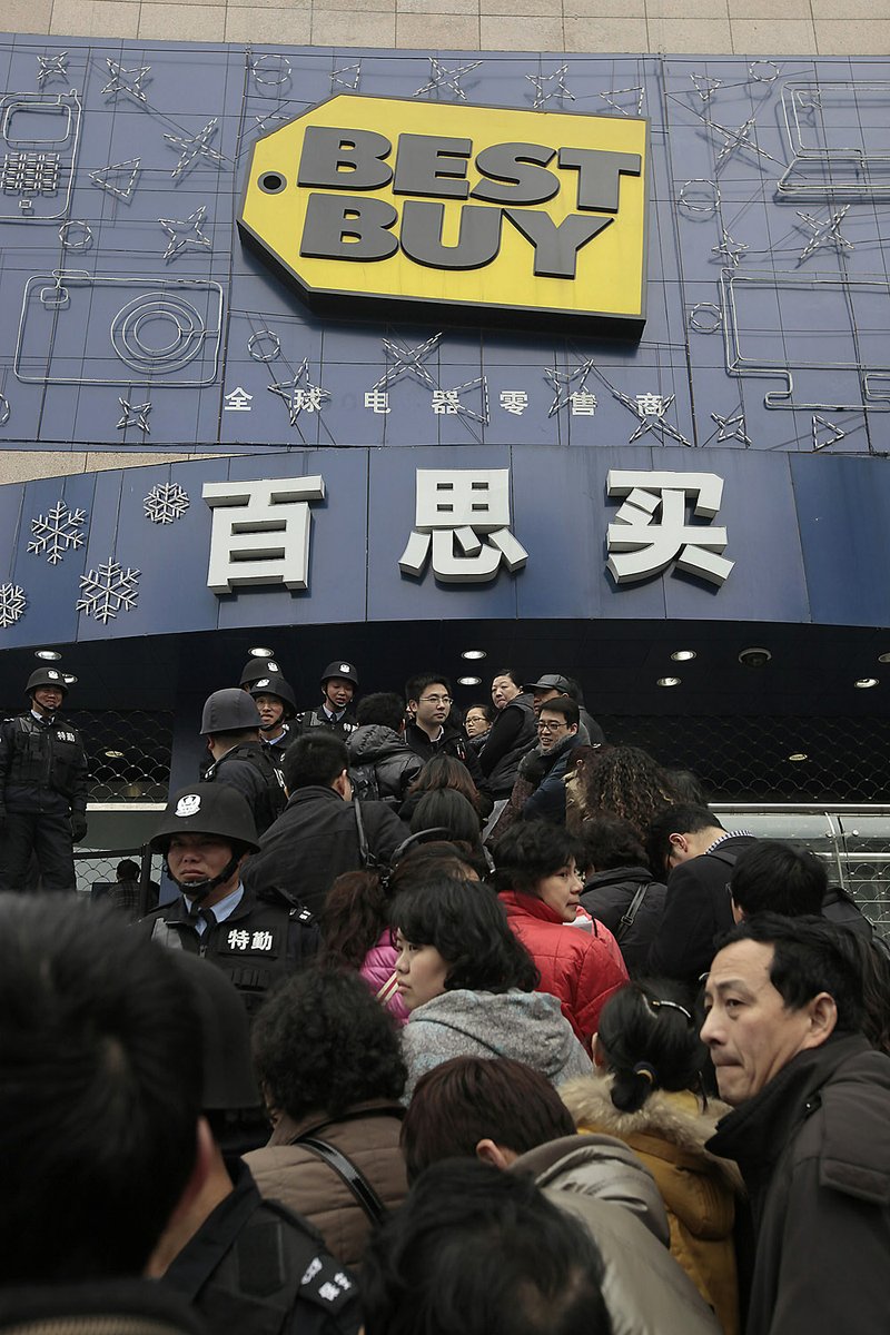Guards in Shanghai keep an eye on people lined up outside a Best Buy store Friday to get help from customer service.

