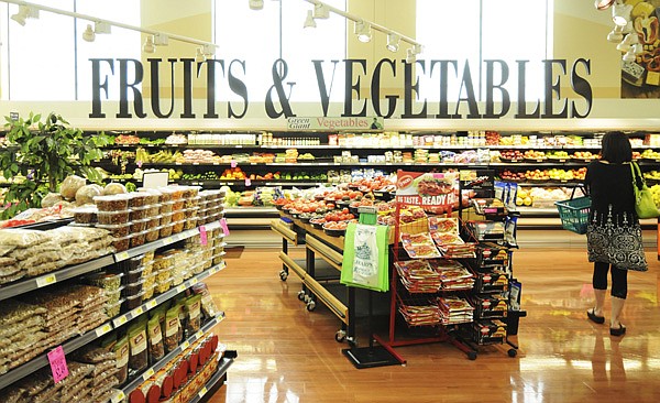 A shopper browses through the fruit and vegetable aisle Wednesday at Harp’s in Springdale. Price hikes for fresh fruit and vegetables are often tied to weather issues.