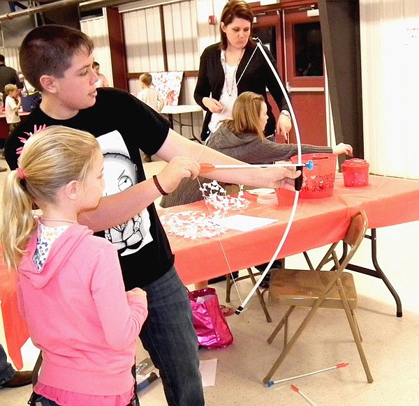 Jackson Stickles helped Megan McCullom with her archery at the Benton County 4-H Valentine Carnival on Feb. 19.