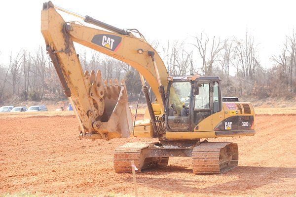 A worker with Arco Excavation and Paving in Springdale operates an excavator Wednesday, Feb. 23, to compact a layer of clay as construction begins for a planned Walmart location south of the Arkansas 59 and Arkansas 59 Business intersection in Gentry.