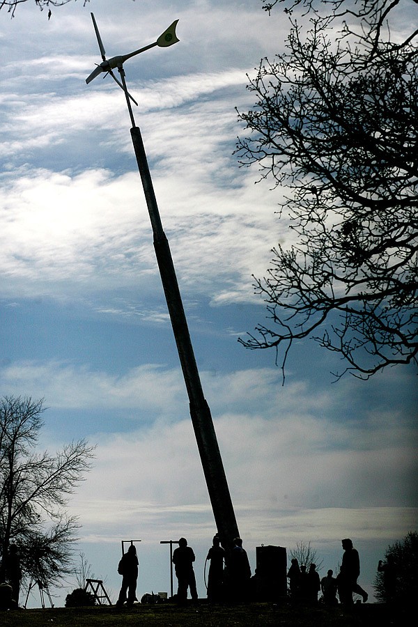 John Brown University students and faculty watch as a 60-foot wind turbine is raised on the Siloam Springs campus. The turbine, which was donated by Sonkyo Energy, will power lights on a walking trail around campus.