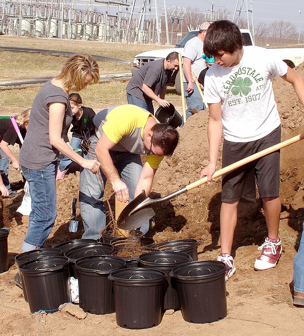 Gentry mayor Kevin Johnston (center), with his wife Lori and Dakota Smith, help plant trees.