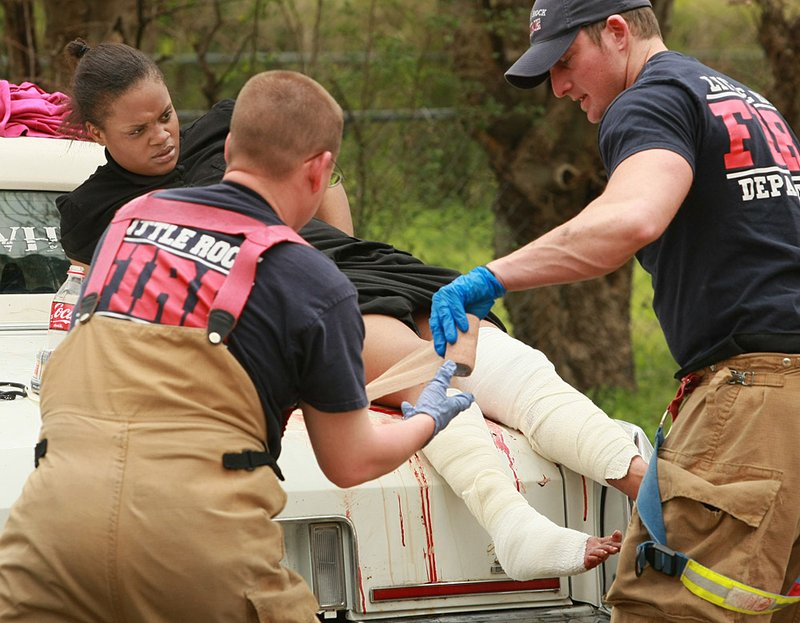 Firefighters tend to a dog-attack victim Friday near 13th and Pulaski streets in Little Rock. 