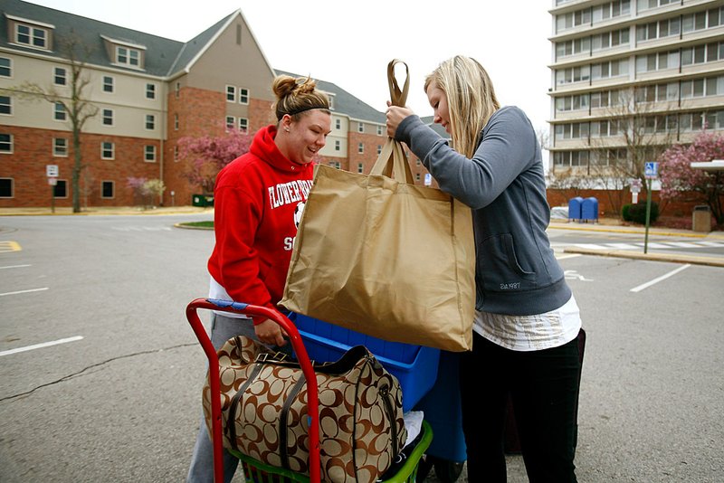 University of Arkansas sophomores and resident advisers Nicole Cooper (left) of Flowery Branch, Ga., and Robin Massingill of Bentonville move their belongings back to their rooms in Maple Hill South residence hall on the Fayetteville campus Sunday after returning from spring break. 