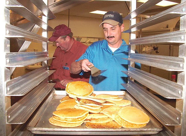 Lions Club member Mark Burden tosses pancakes from the griddle onto the serving pan during the annual pancake supper on Thursday in Gentry. Terrell Shields is frying pancakes in the background. Proceeds raised by the club are used to pay for eye glasses and eye procedures for those who cannot afford them.