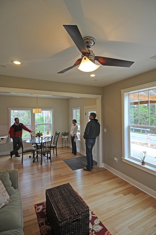 Cam Mosley, left, looks at a house at 25 Gregg Ave. on Wednesday in Fayetteville while visiting with real estate agent April Hamm, middle, and builder Todd Jacobs. Utility costs in the house are estimated to be $1,000 per year.