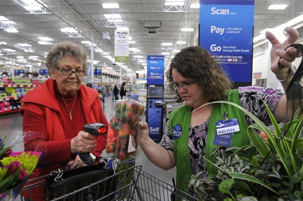 Melissa McIntosh, right, assists Gwen Spillman of Bella Vista with her first time using Sam’s Club’s new self checkout system on Wednesday in Bentonville. Sam’s Club introduced self-checkouts two weeks ago.