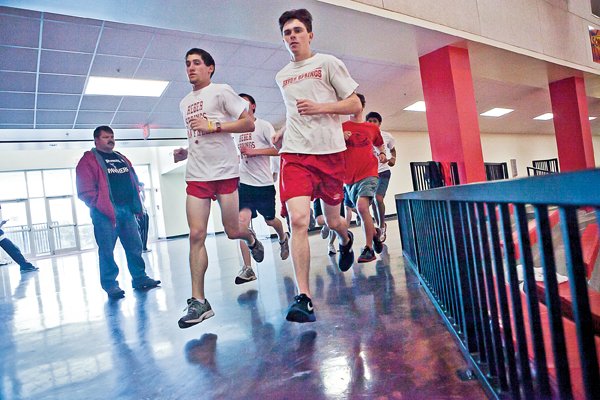 Michael Dorsey, right, a senior, and Jake Sanders, a junior, lead their running team around the track at Heber Springs High School during practice.