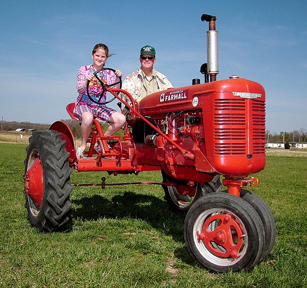 Madison Bunch, 10, with her grandfather, Glenn Smith, drive a 1945 B Farmall tractor on the grounds of Tired Iron of the Ozarks, in Gentry, in preparation for the annual spring show this weekend. The tractor, outfitted by Smith with two seats, and a clutch and brake pedal on each side, is the club's new "driver's ed tractor." Rides will be offered without charge to children, 8 and above, this weekend.