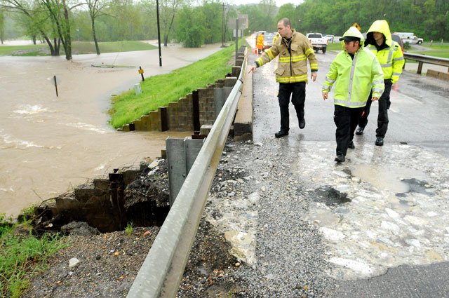 Greg Mills, left, a Bella Vista firefighter, points to flood damage to the Arkansas Highway 340 Bridge over Tanyard Creek shortly before it was closed to traffic in Bella Vista on Monday. The decision to close the bridge was made by the Arkansas Highway and Transportation Department which sent crews to work on the bridge shortly after its closing. For more photos, visit <a href="http://photos.nwaonline.com">photos.nwaonline.com</a>.