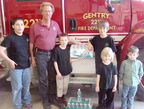 Matthew Nance (left), Fire Chief Vester Cripps, Ben Philpott, Wyatt Philpott, Kayla Philpott and Houston Nance pose for a photo when the Outdoor Adventures 4-H club donated bottled water to the Gentry Fire Department. 