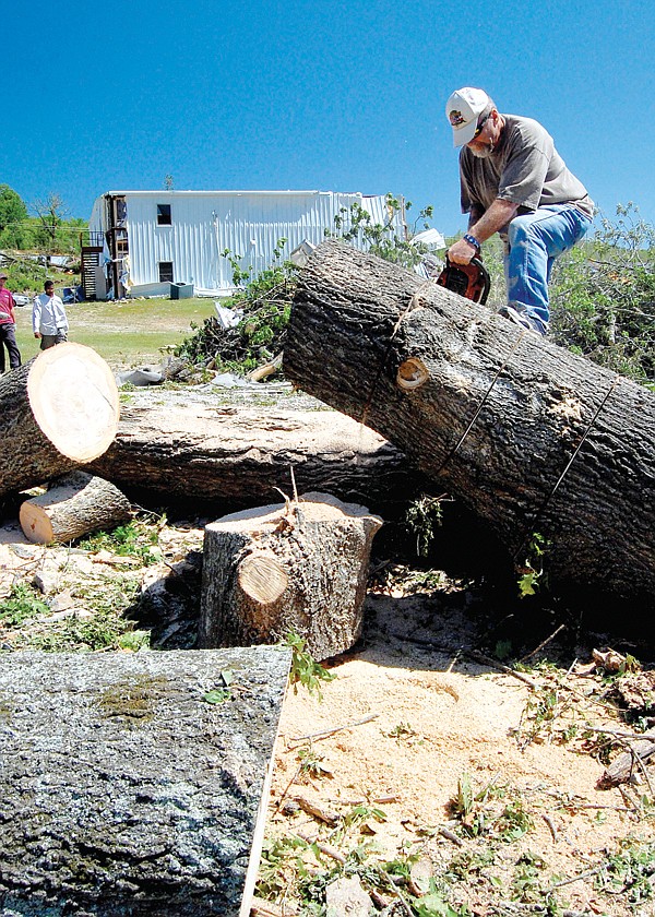 Carl Smith of Hot Springs Village volunteers his time to chain-saw a tree at Teen Challenge of Arkansas on Friday.