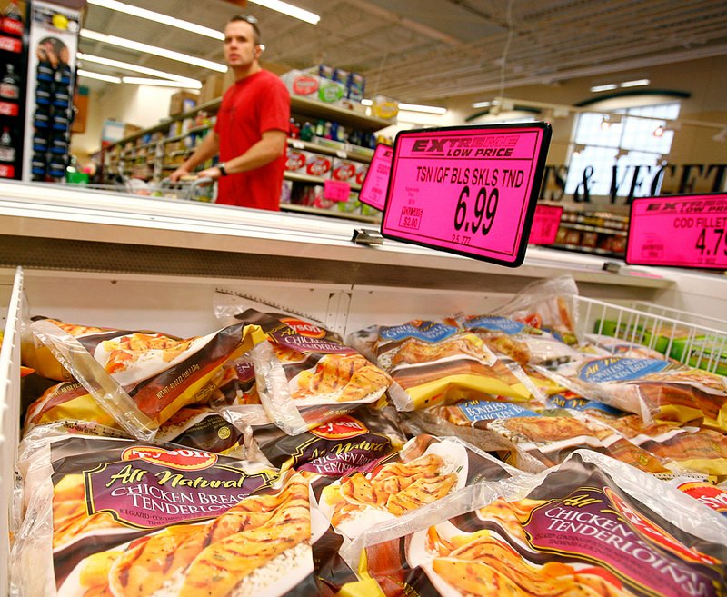  A shopper looks over items as he passes a display of bags of Tyson Foods frozen chicken inside the Harps store in Springdale on Sunday.