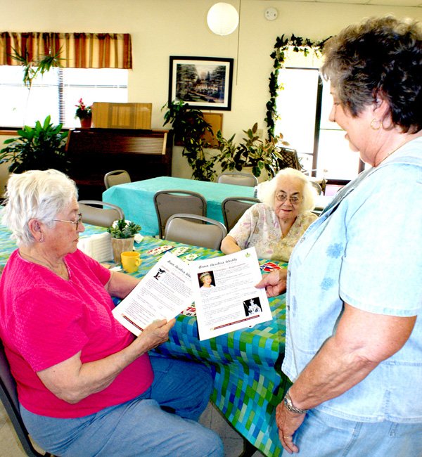 Mary Kay Kelley, right, director of the Billy V. Hall Senior Activity Center in Gravette shares copies of "Brain Aerobics Weekly" with Estelle Marney and Shirley Ball at the Center. 