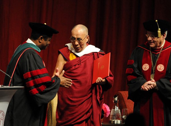 Carl Johnson, left, chairman of the University of Arkansas Board of Trustees, and Alan Sugg, right, president of the University of Arkansas System, present the Dalai Lama with an honorary degree Wednesday at Bud Walton Arena in Fayetteville. The Tibetan spiritual leader in two public sessions called for activism and nonviolence.