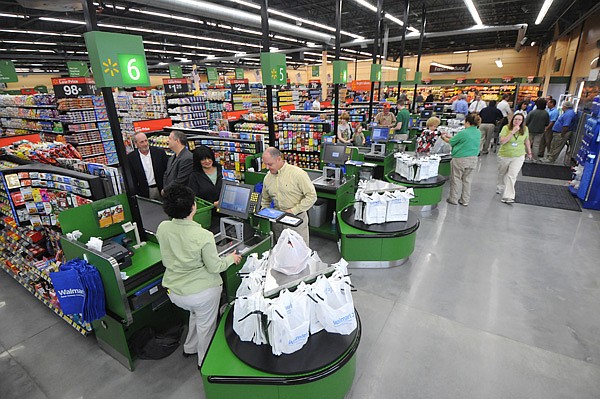 The first few customers check out Wednesday at the new Walmart Market in west Fayetteville. The store is Walmart’s first to rebrand the Neighborhood Markets.