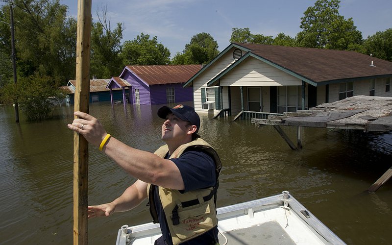 Firefighter Chris Hite checks the water depth in a flooded Vicksburg, Miss., neighborhood Wednesday. The Mississippi River is expected to crest today in Vicksburg at 57.1 feet. 
