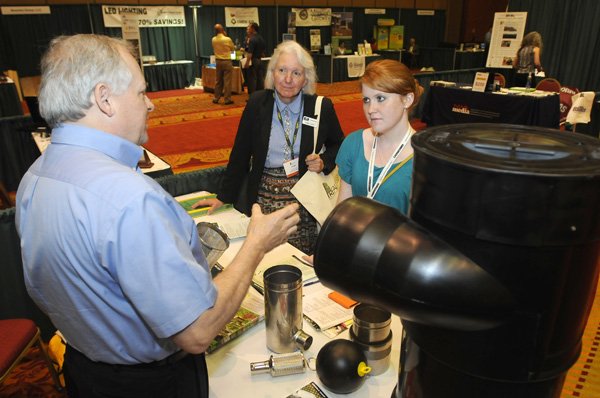 Carter L. Pannell, from left, with Pannell Asscociates, talks Friday with Linda Lloyd of Kaufmann Realty in Bella Vista, and Scarlett Kerby with Greenzine magazine about rainwater recovery systems during the REALgreen Conference and Expo at the John Q. Hammons Center in Rogers. The event continues today from 7 a.m. to 3 p.m.\
