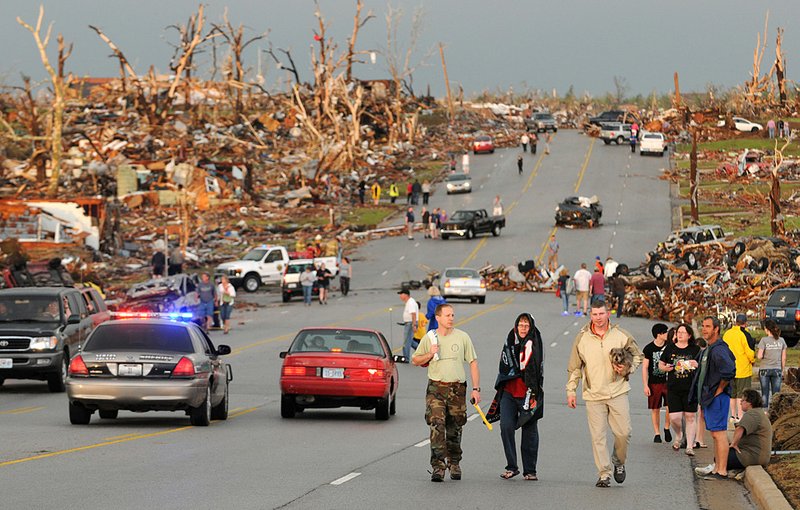 Residents of Joplin, Mo, walk west on 26th Street near Maiden Lane after a tornado hit the southwest Missouri city on Sunday evening. The tornado tore a path a mile wide and four miles long destroying homes and businesses.