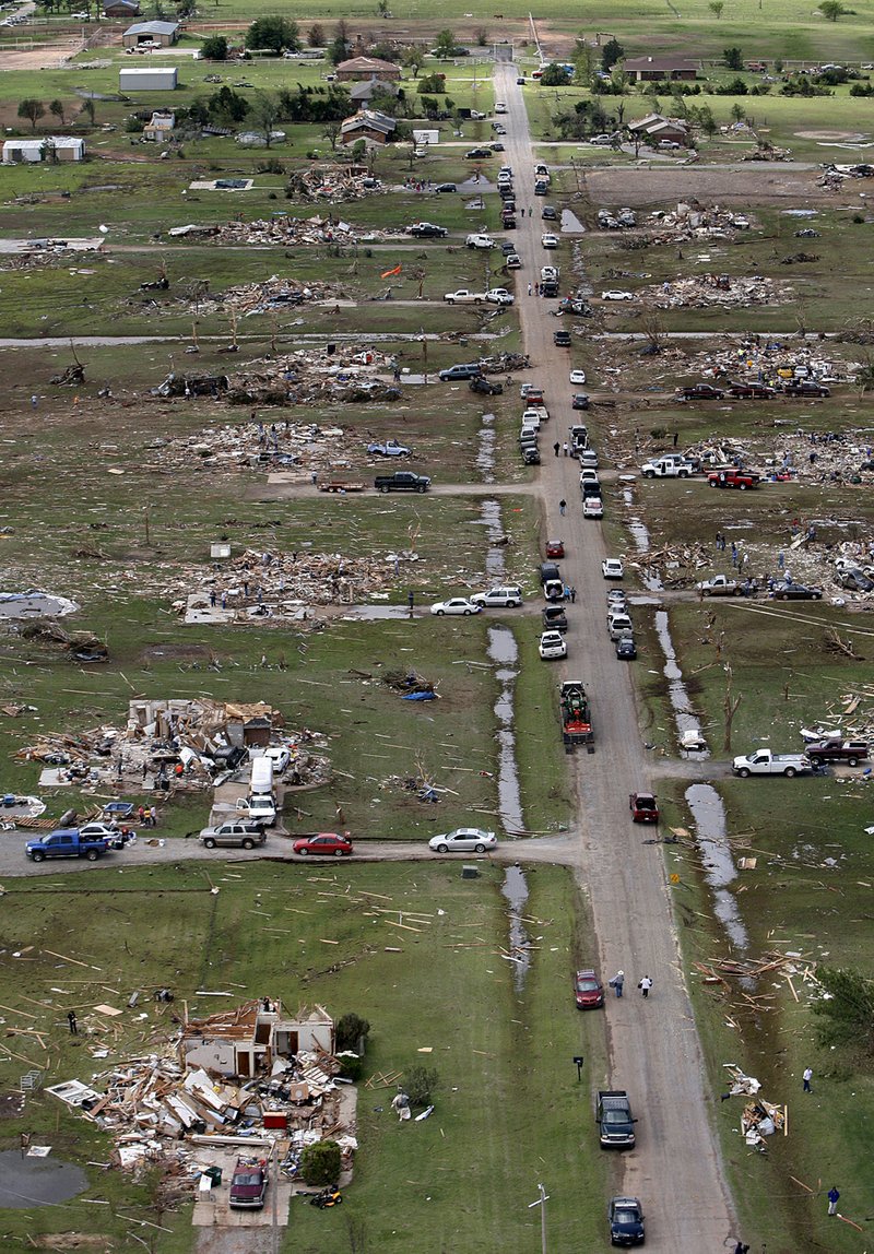 People look over a damaged house east of Piedmont, Okla., on Wednesday. The house was one of dozens damaged Tuesday by storms that killed nine people in Oklahoma. 