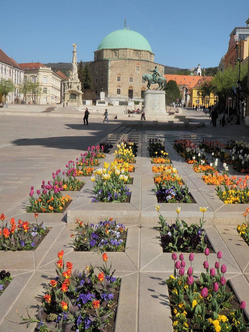 The main square in the Hungarian city of Pecs showcasing an Ottoman 
mosque converted to a church. Flowers add a color accent.