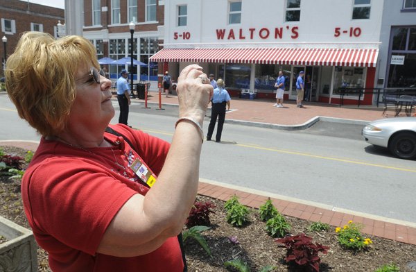 Penny Larson, of Wausau, Wis., takes photographs Wednesday in front of the Walmart Visitors Center in downtown Bentonville. Larson was attending her first shareholders meeting after working for Walmart for 23 years.