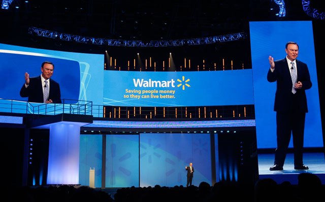 Mike Duke, President and CEO of Wal-Mart, center, speaks to shareholders as his image appears on screens left and right in Fayetteville, Ark., Friday, June 3, 2011. (AP Photo/Danny Johnston)